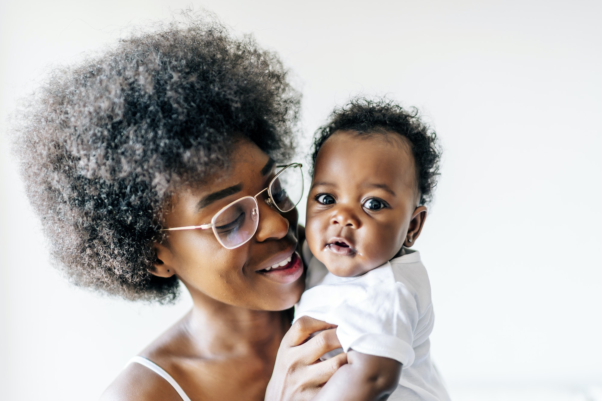 African-American mother taking care and loving her baby against a white background