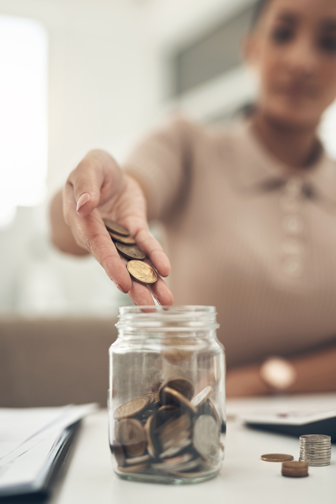 Closeup shot of an unrecognisable businesswoman filling a glass jar with coins in an office